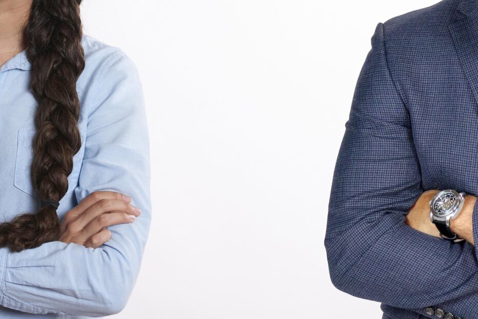 Imagem de duas pessoas em uma pose fechada, uma com camisa azul e cabelo trançado, e outra com um traje formal, transmitem uma sensação de seriedade e profissionalismo.
