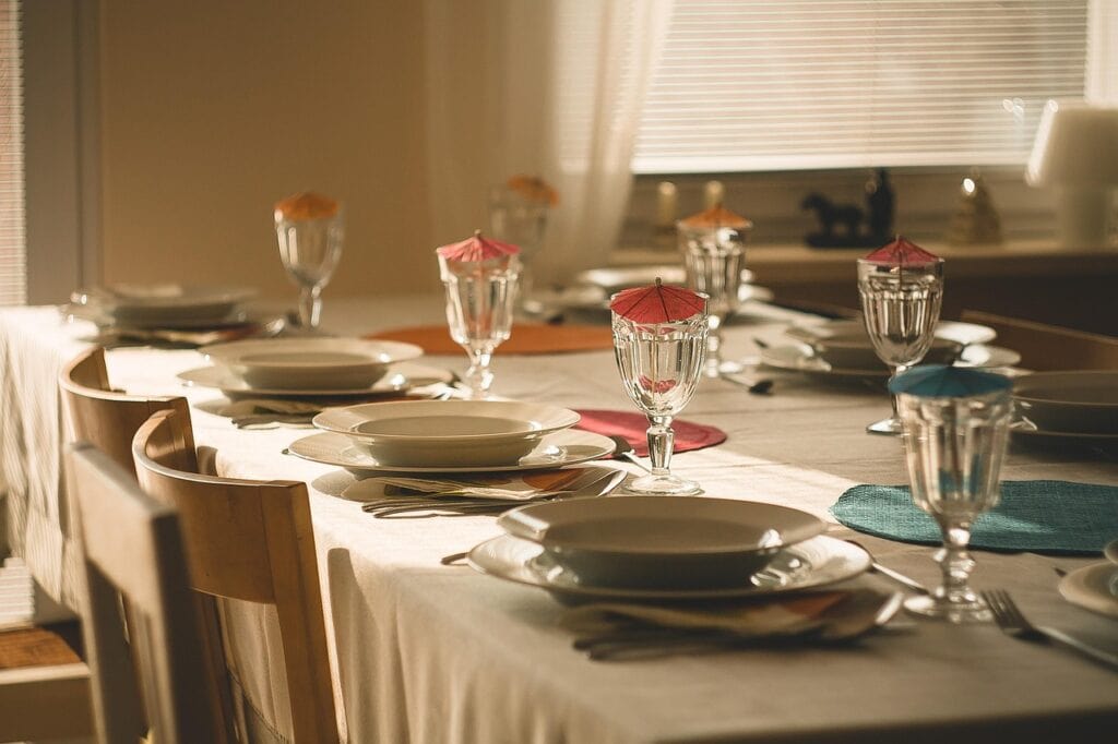 Mesa posta elegantemente para um jantar especial, com pratos brancos, copos decorados e toalha clara.